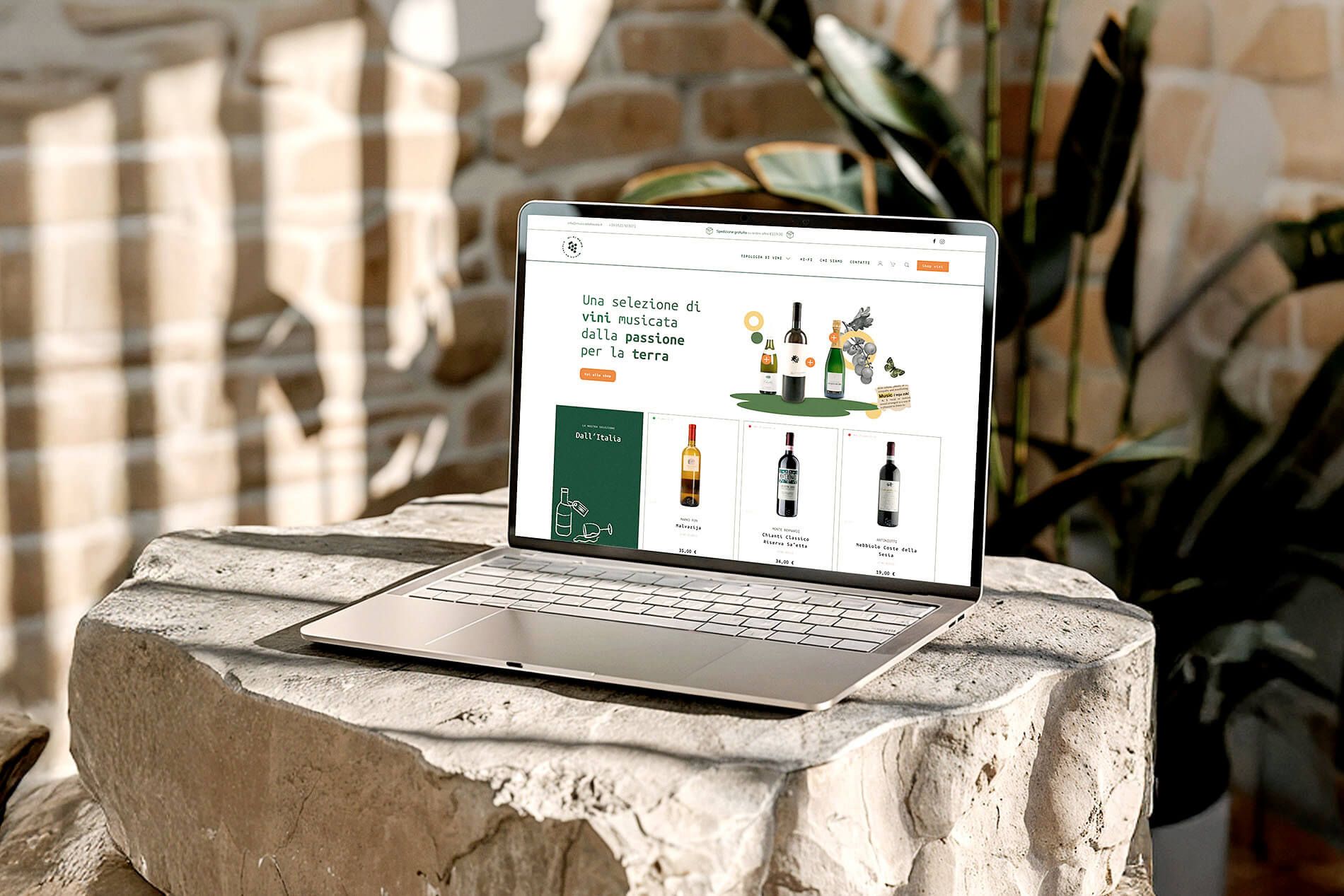 Laptop su un blocco di pietra con il sito musicadatavola.it aperto, che mostra una selezione di vini italiani in vendita online.